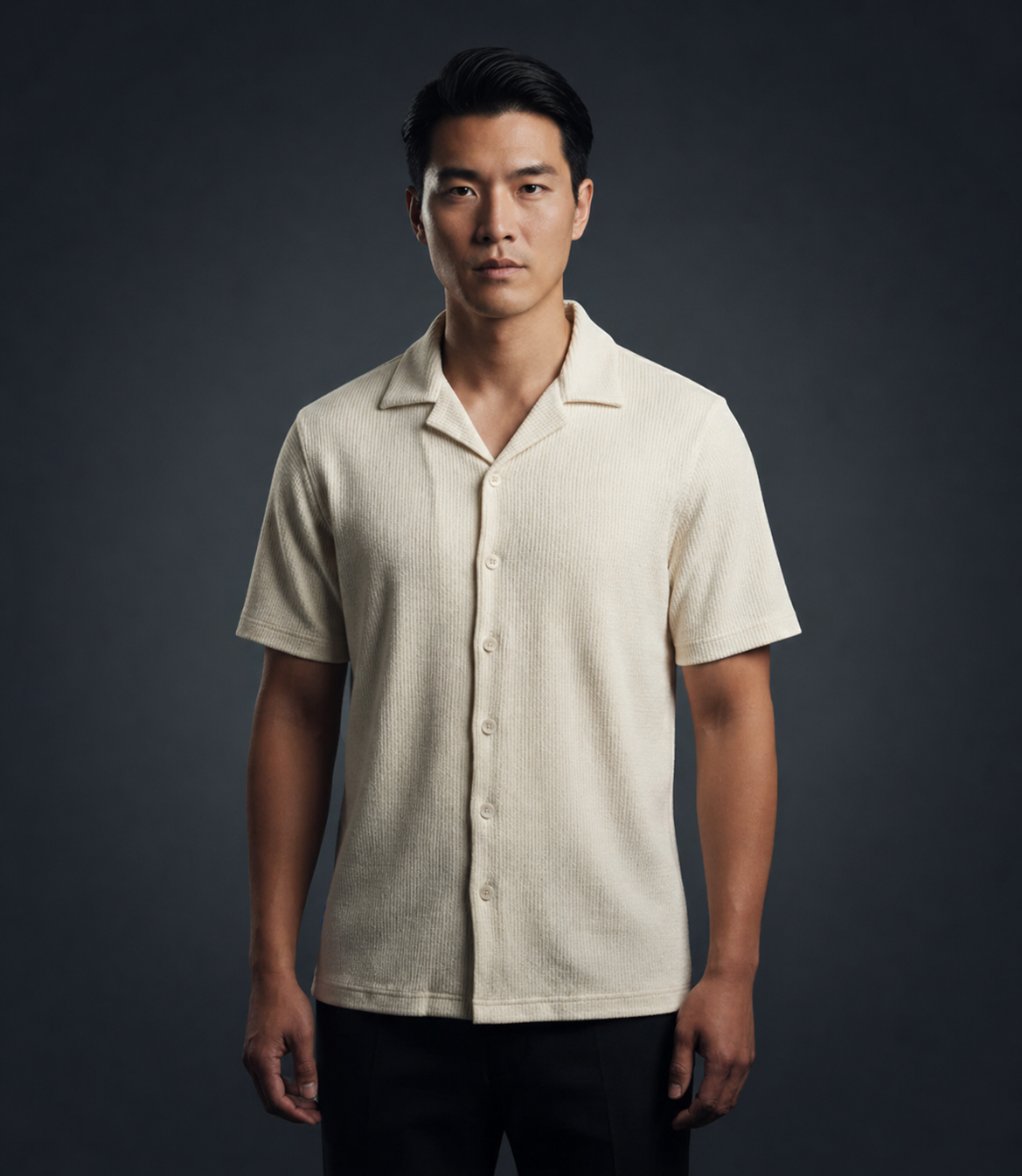 Man wearing a beige short-sleeve shirt against a dark background